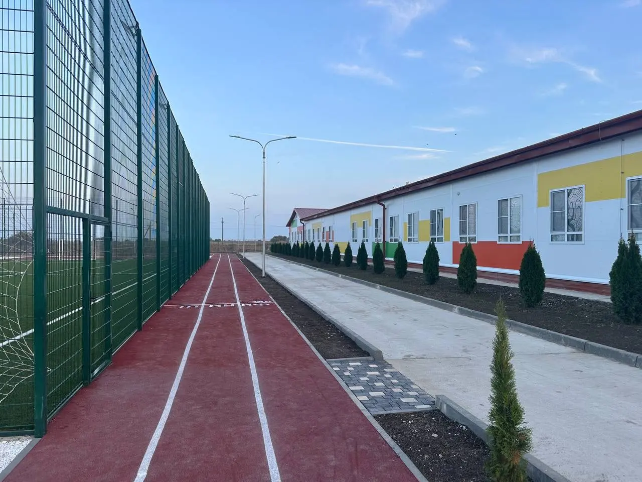 Running track along the building and the football pitch fence